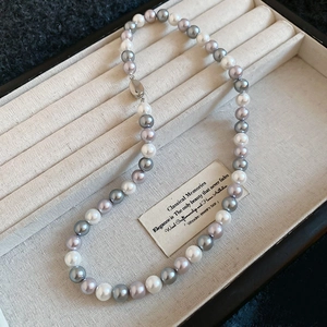 Detailed view of multi-color pearls in white, grey and lilac on a textured jewelry tray