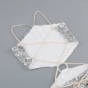 Detailed close-up of silver sequin halter top with cross strap design on grey surface