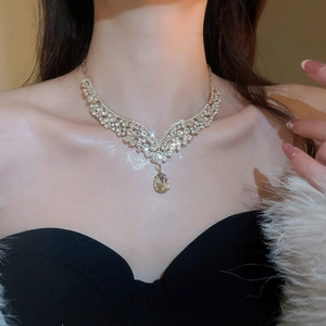 Close-up of elegant V-shaped gold necklace with sparkling waterdrop pendant on model