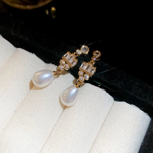 Detailed close-up of 18k gold plated drop pearl earrings with sparkling crystals