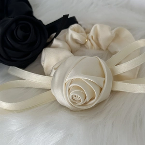 Close-up of elegant cream satin scrunchie with 3D rose flower and long ribbon ties