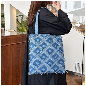 Detail of denim tote bag showing star pattern stitching and fringe trim on the material
