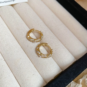 Macro detail of gold hoop earrings with twisted rope design, pearls and zircons
