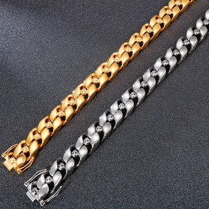 Macro detail of silver and gold Cuban link bracelets with gothic skull engravings