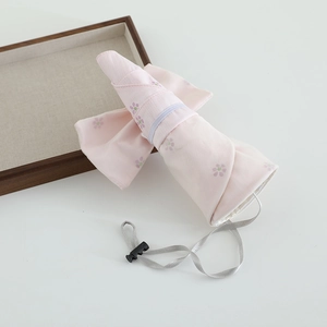 Folded pink floral sun hat for girls featuring adjustable wind rope and portable design