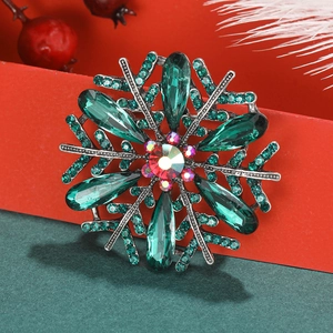 Macro shot of silver snowflake brooch with emerald teardrop crystals and red center gem