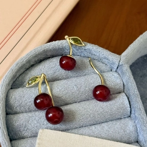 Elegant cherry pendant earrings with red resin gems and golden leaves on grey velvet