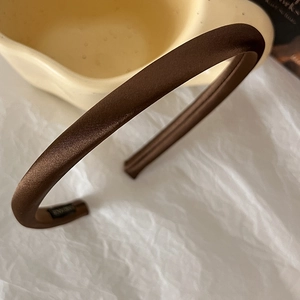 Detail of elegant mocha brown satin headband featuring a glossy silk-like fabric texture