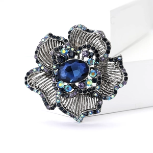 Detailed close-up of a vintage floral brooch featuring blue rhinestones and silver alloy