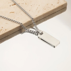 Polished silver stainless steel rectangular pendant necklace on a textured stone base