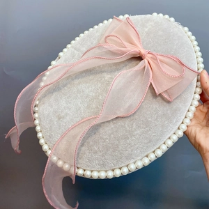 Detail of a pink organza bow hair clip with faux pearl trim on a soft velvet base