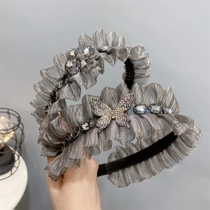 Detail of silver pleated fabric headband with butterfly rhinestones and flower crystals
