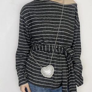 Detailed view of a silver heart pendant necklace with rhinestones on a striped shirt