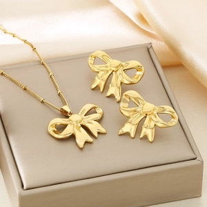 Detailed view of golden bow necklace and earrings set on a premium jewelry box background