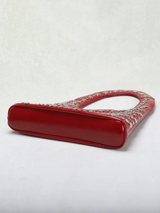 Macro shot of silver metal rivets on dark red leather shoulder bag with smooth texture