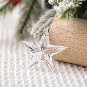 Macro shot of a clear faceted star pendant on snowy pine branches and wooden blocks