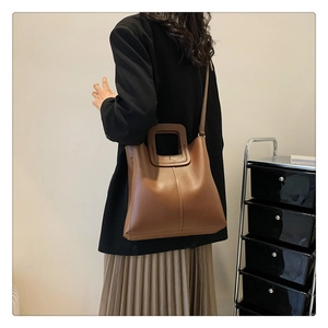 Lifestyle shot of a woman carrying a brown vintage-style bucket bag over her shoulder