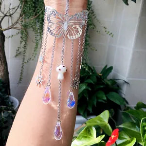 Detail of silver hollow butterfly tassel arm chain with crystals and mushroom charms