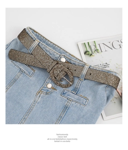 Detail of glittery gold PU leather belt with rhinestone inlay and oval metal buckle