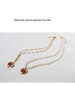 Detail of vintage enamel heart pendants with rose pattern on paperclip and pearl chains