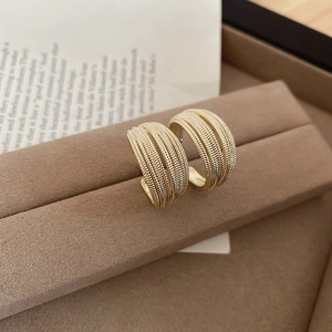 Macro detail of gold-plated multi-layer C-shaped hoop earrings with woven texture