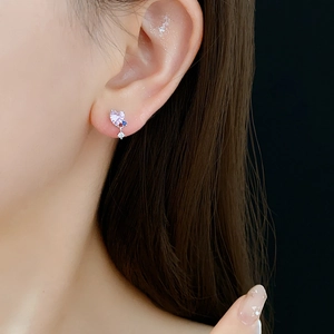 Close-up of elegant pink heart-shaped crystal earring with zircon stones on female ear