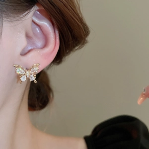 Close-up of golden butterfly earring with white zircon on ear showing petite style