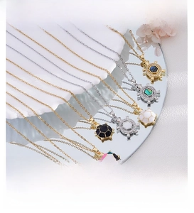 Détails de pendentifs tortue colorés sur chaînes dorées et argentées sur une surface miroir