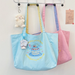 Detail of embroidered canvas tote bag with cake pattern and plush flower pendant