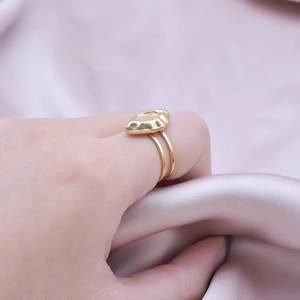 Detailed view of a gold geometric oval ring featuring an irregular wavy design on silk background
