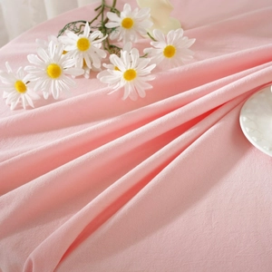 Detail of pink washed cotton tablecloth with soft texture and elegant natural drapes