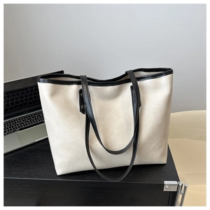 Detail of cream tote bag with black trim showing premium leather texture and large capacity