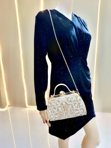 Detail view of gold evening bag with rhinestones, pearls and metallic handle