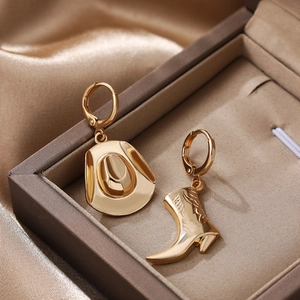 Asymmetric golden western cowboy boot and hat earrings displayed in a luxury jewelry box