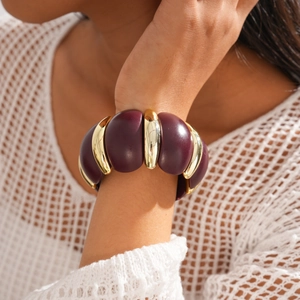Macro view of dark purple resin blocks and gold metal joints on the chunky bracelet