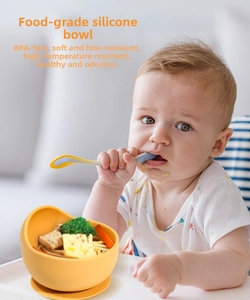 Detail view of a yellow silicone suction bowl for babies with complementary soft feeding spoon