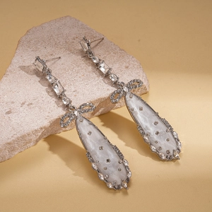 Détail des boucles d'oreilles nœud en zircon avec pendentif goutte sur une pierre