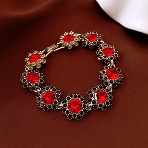 Detail of luxury bracelet with red gemstones and black crystals on vintage gold links
