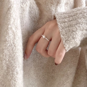 Minimalist 925 sterling silver bean ring worn on finger with soft knit sweater background