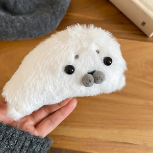 Close-up of a cute white plush seal hair claw clip with soft faux fur and bead eyes