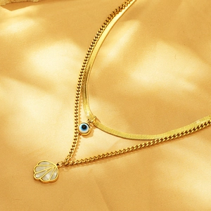 Detail of gold double-layered necklace with shell and blue evil eye charms on gold silk