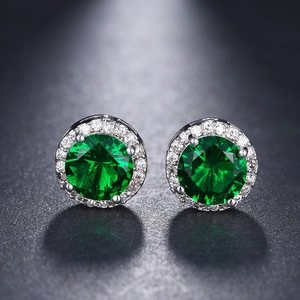 Macro shot of halo stud earrings with round green emerald-cut stones and silver base