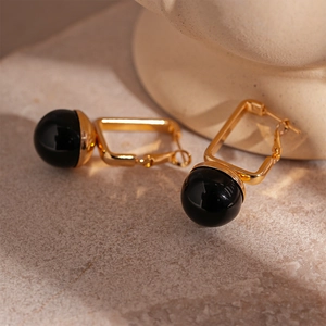 Detailed macro shot of vintage geometric earrings with gold rectangle and black resin beads