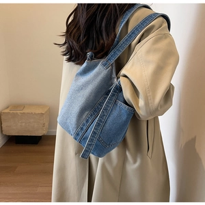 Detail shot of blue denim bucket bag with wide shoulder strap and external pockets