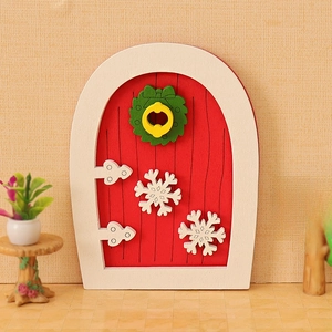 Miniature red Christmas dollhouse door with white frame and decorative green wreath