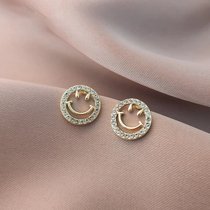 Macro shot of gold hollow smiley face stud earrings with shimmering crystal pavé stones