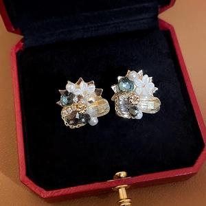 Detail of crystal flower earrings with pearls on red jewelry box velvet lining
