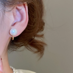 Close-up of elegant large white pearl clip-on earring worn on model's ear