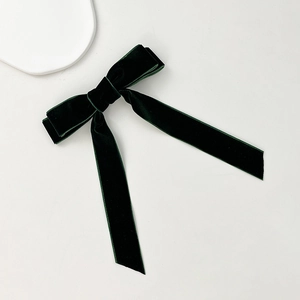Detailed texture of a dark green velvet bow hair clip with long elegant ribbons