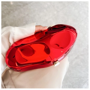 Close-up of a glossy red acrylic evening clutch with a stylish golden metal clasp